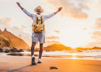 young-man-arms-outstretched-by-sea-sunrise-enjoying-freedom-life-people-travel-wellbeing-concept